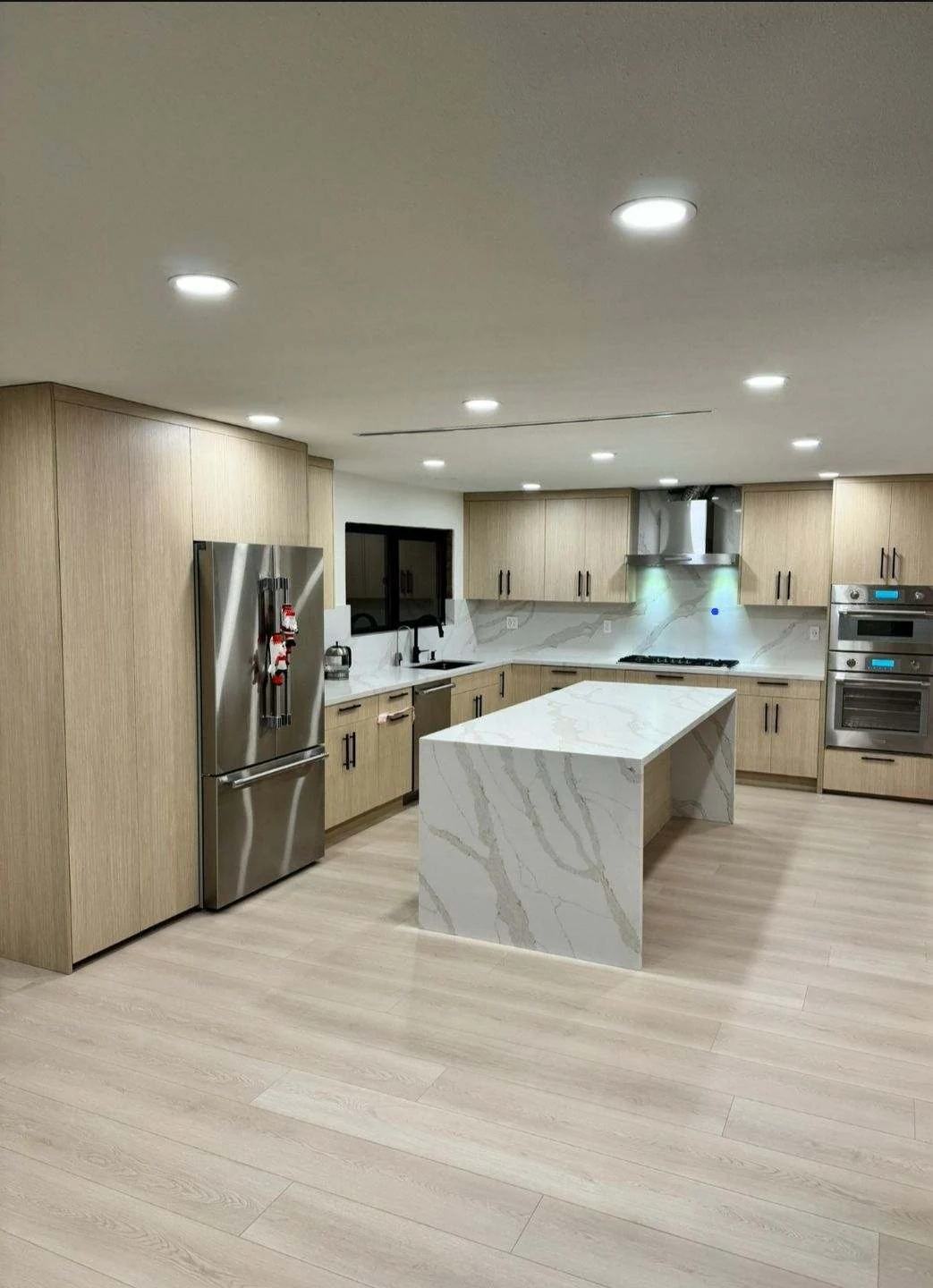 Completed light oak kitchen remodel with waterfall island and recessed lighting