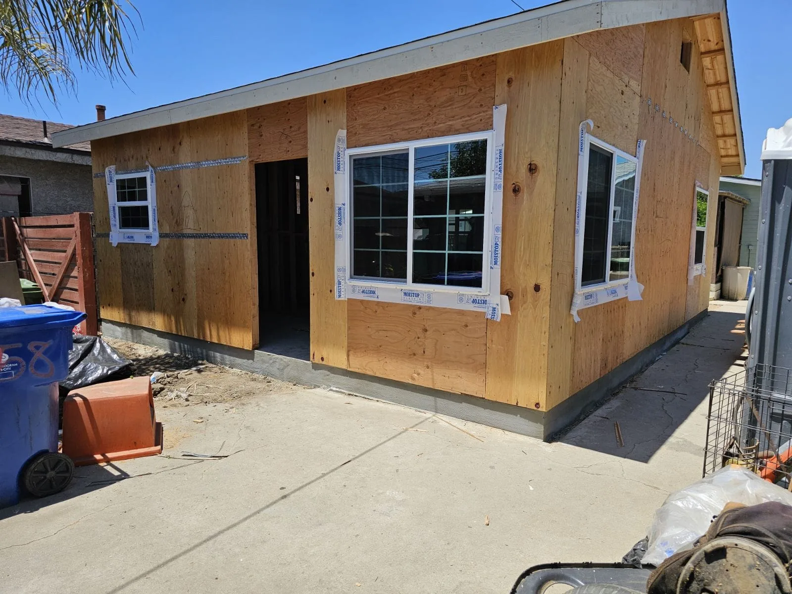 Detached ADU exterior under construction with plywood sheathing and windows installed