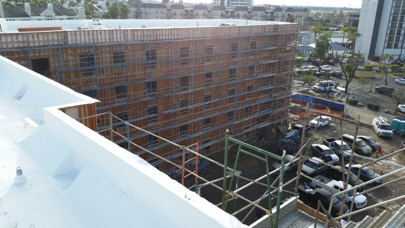 Large multi-story commercial framing structure viewed from a nearby rooftop