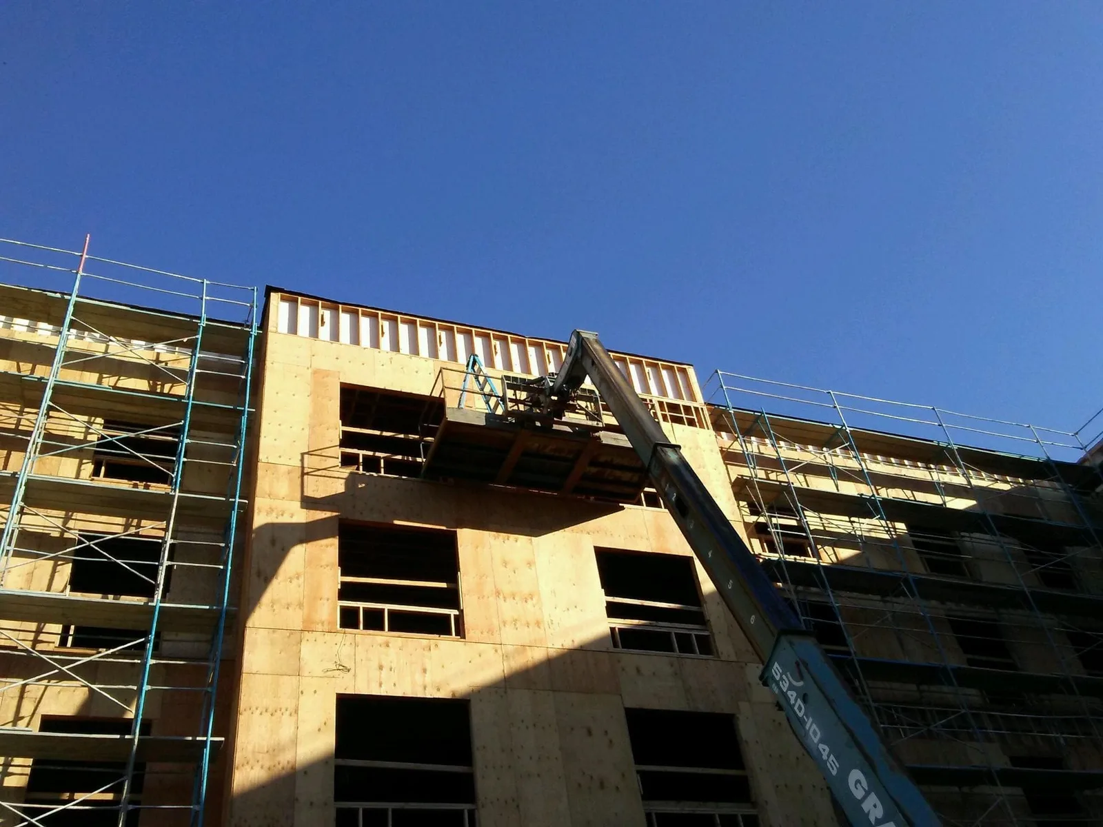 Multi-story commercial wood framing with scaffolding and a material lift