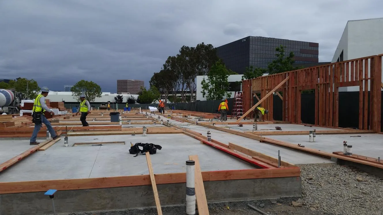 Construction crew laying out wood framing on a large concrete slab